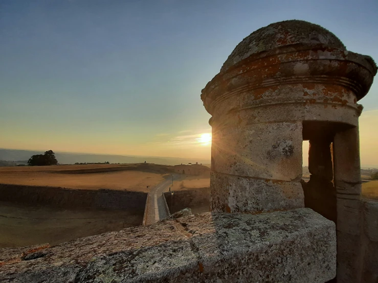 an old stone building with the sun going down in the background