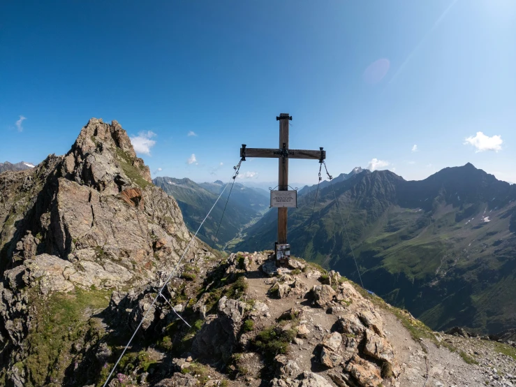 a cross with a sign above it in the mountains