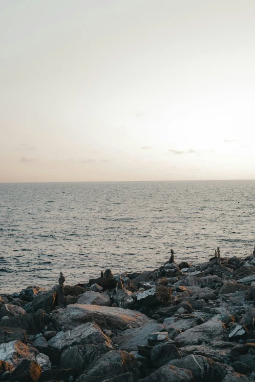 people on rocks watching the ocean in a grey sky