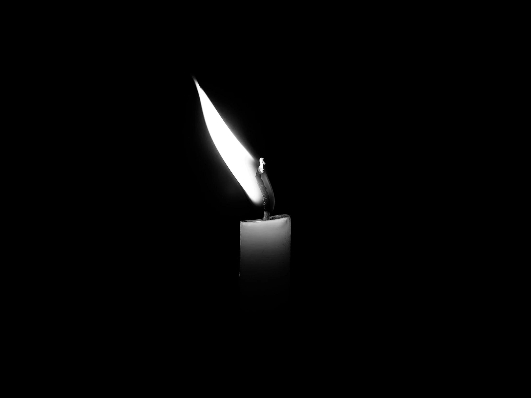 a candle is lit in the dark on a black background