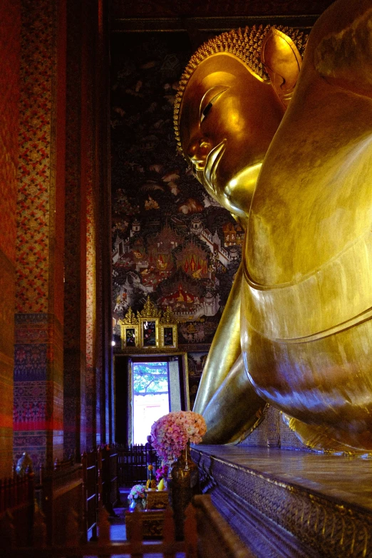 a large gold buddha statue next to a window