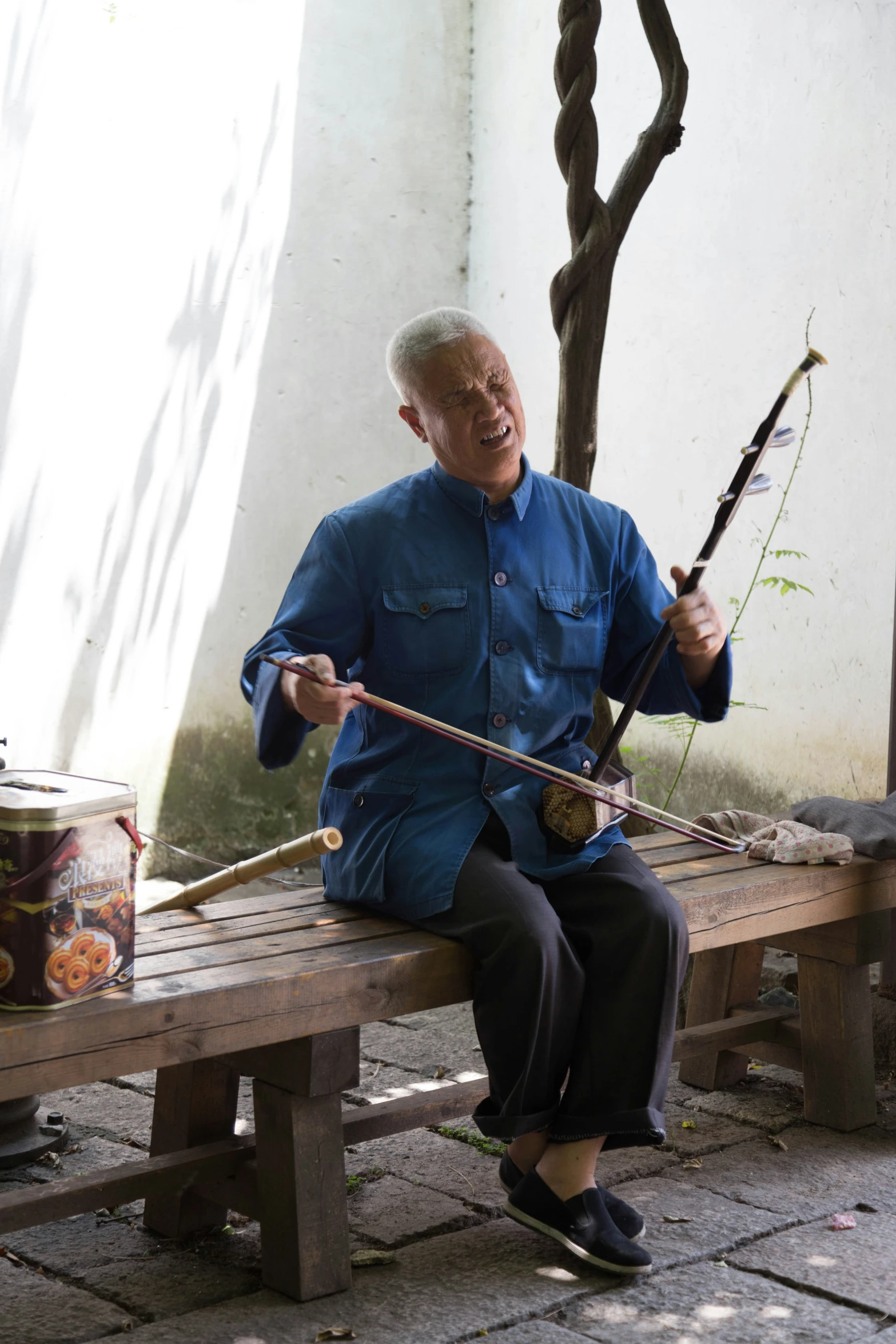 the older man sits on the bench and holds a fishing rod