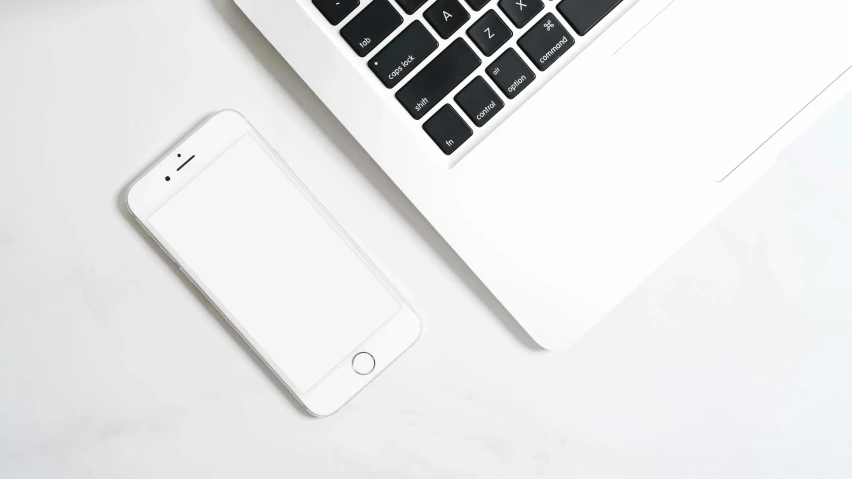 a laptop computer sitting next to an iphone