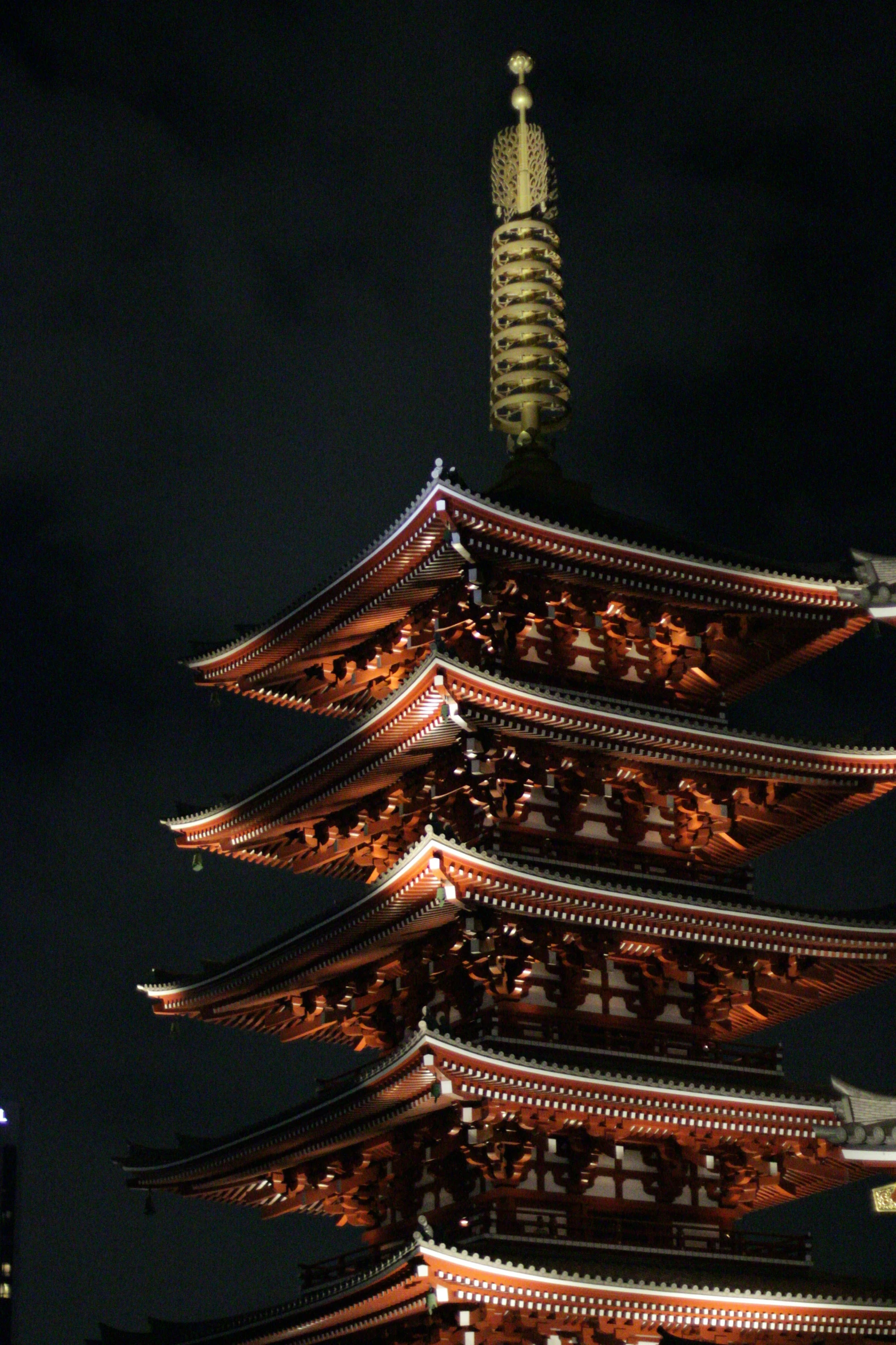 a tall pagoda tower with a clock tower in the distance