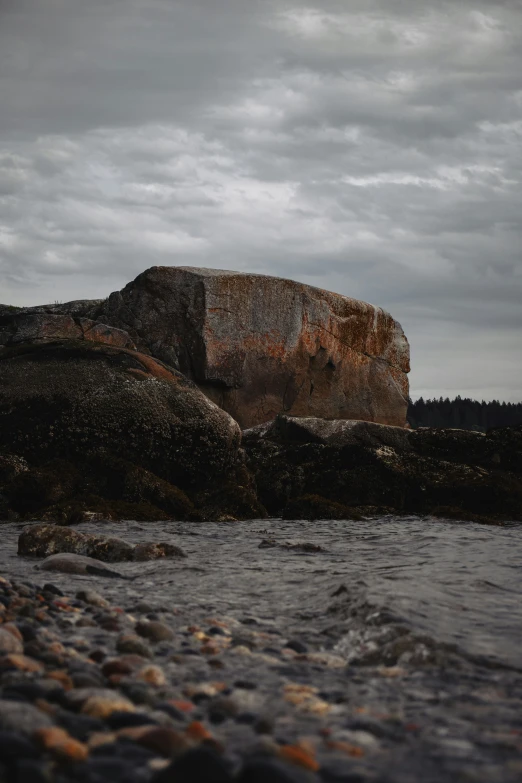 rocks and rocks sitting on the shoreline under cloudy skies