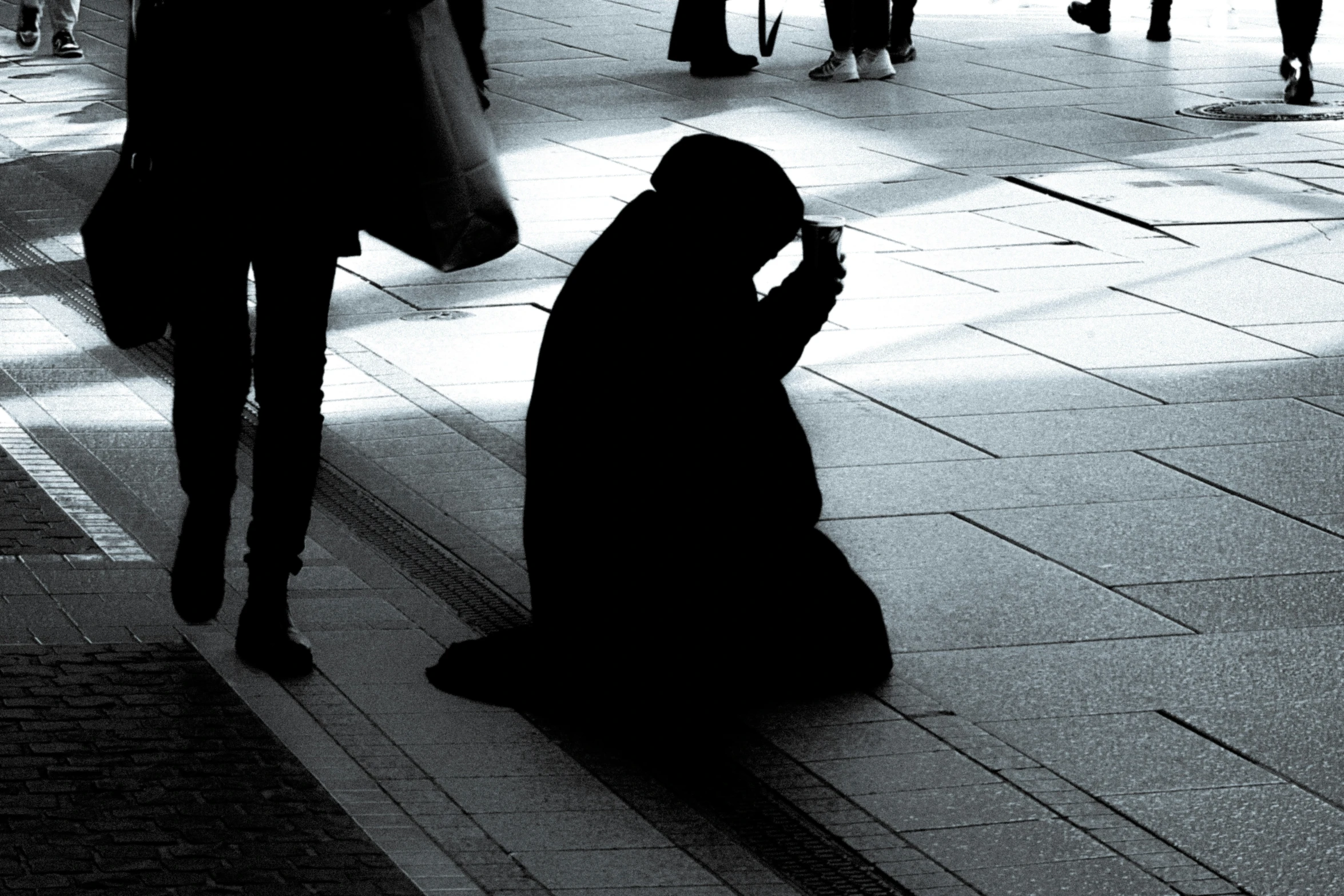 a silhouetted person in a veil sitting on a floor looking at a cell phone