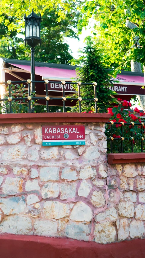 a stone wall with a sign in arabic near a building