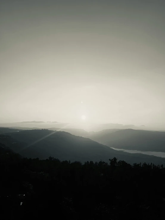 the sun shines in a dark, gloomy sky over mountains