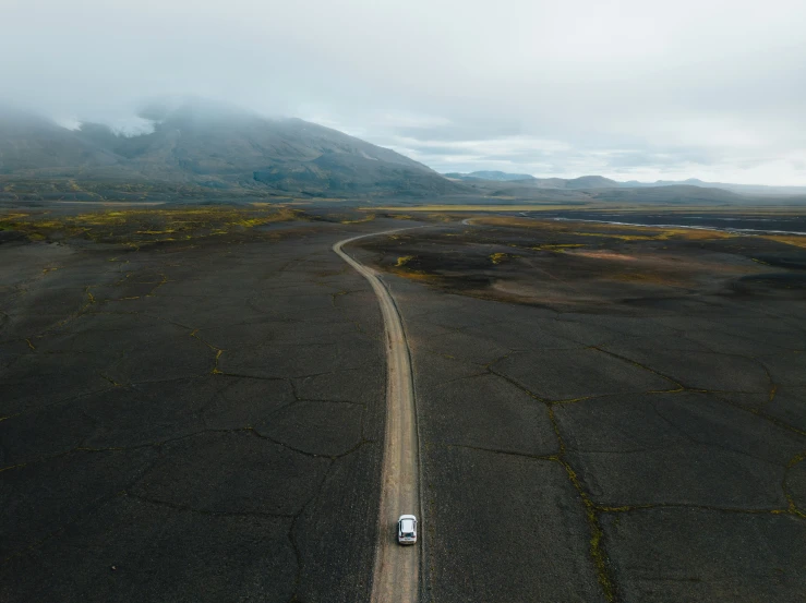 a vehicle on the road in a field by a mountain