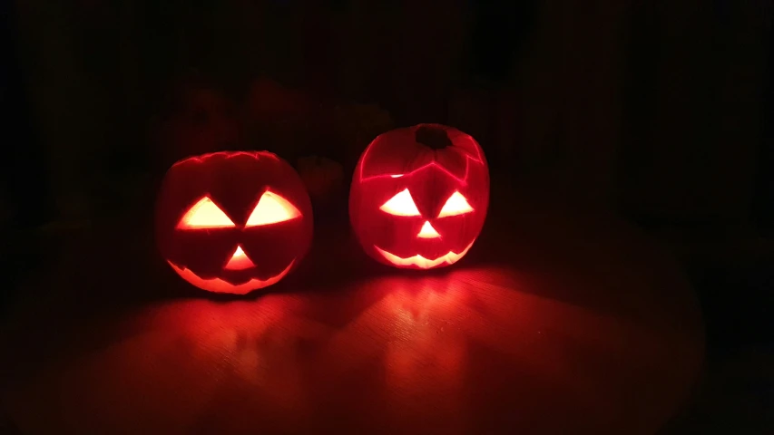two carved pumpkins lit up with one light