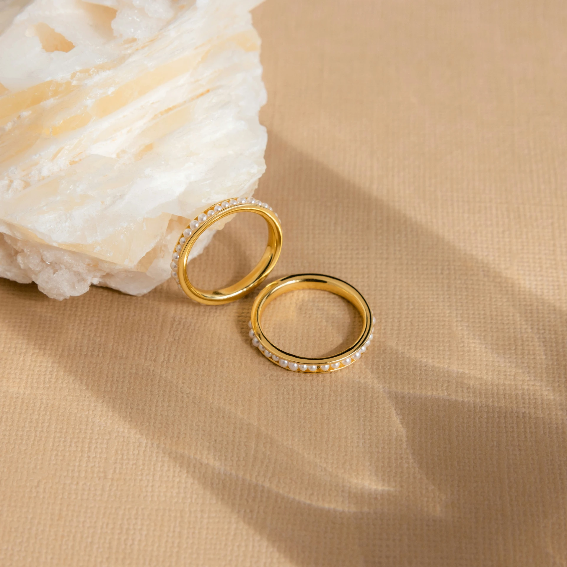 an open gold ring sitting next to some rock