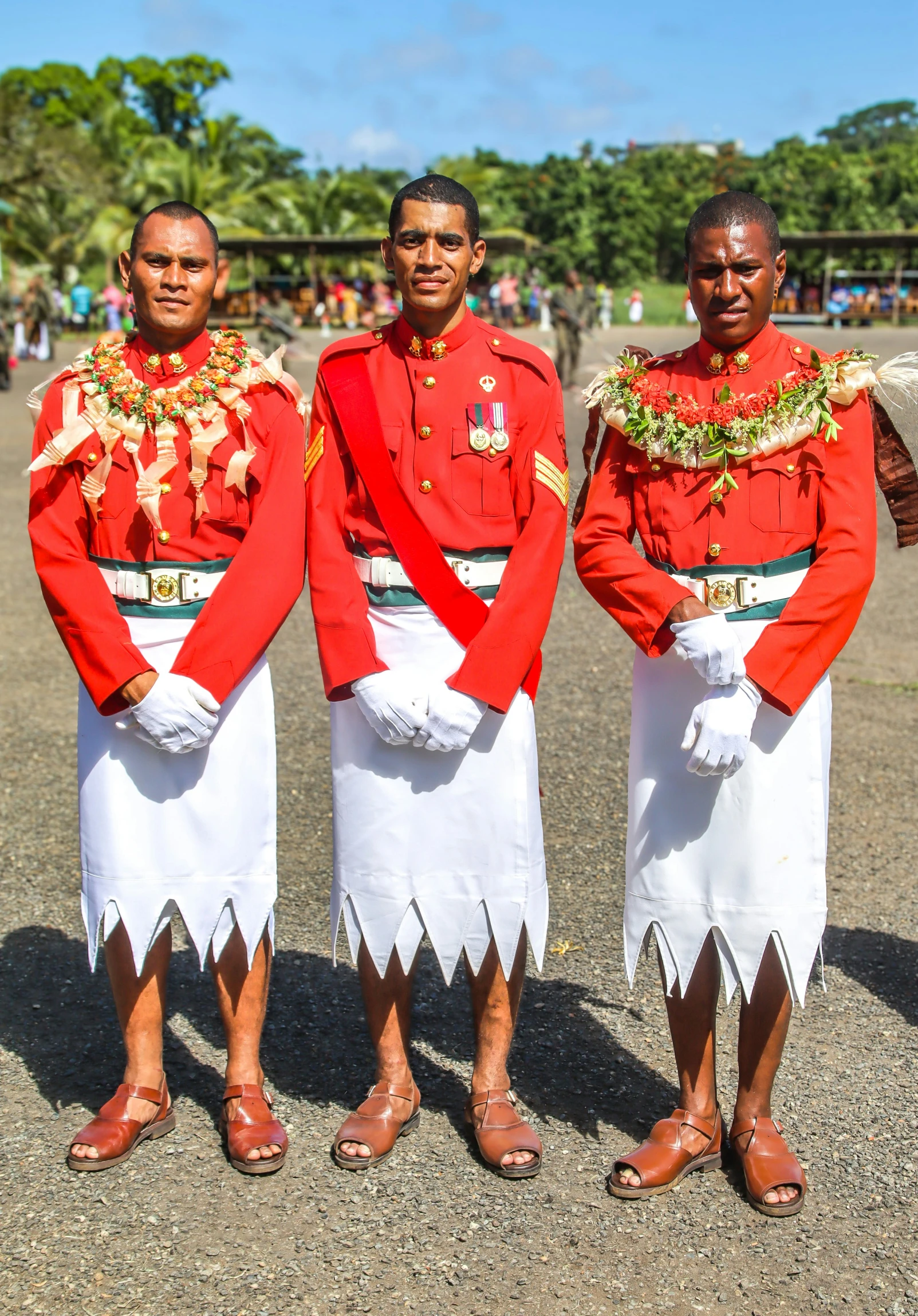 four men dressed in uniforms and necklaces with palm leaves around their neck