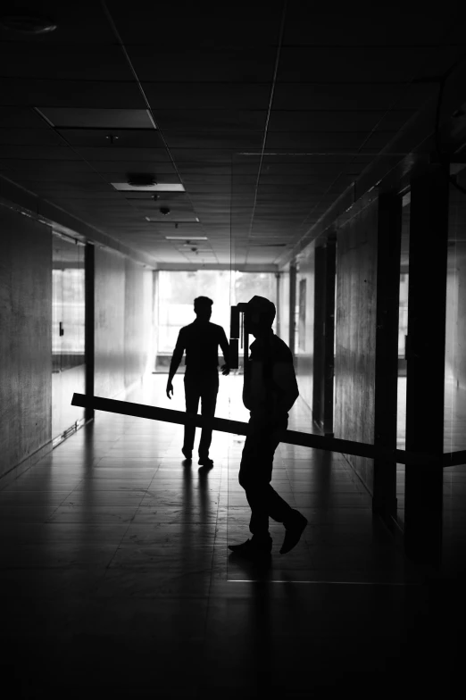 black and white po of two men walking down an enclosed walkway