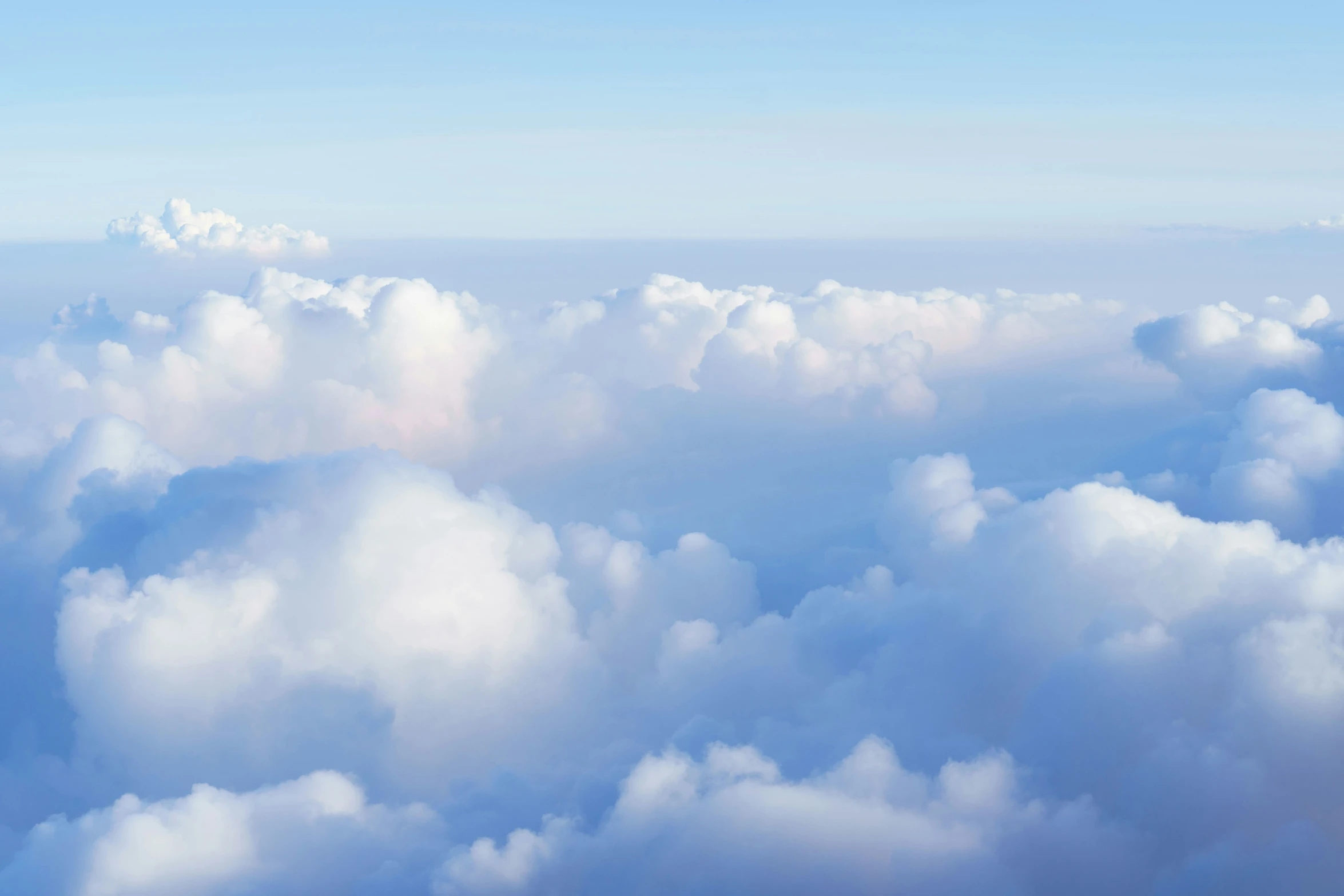 view from an airplane of the sky full of clouds