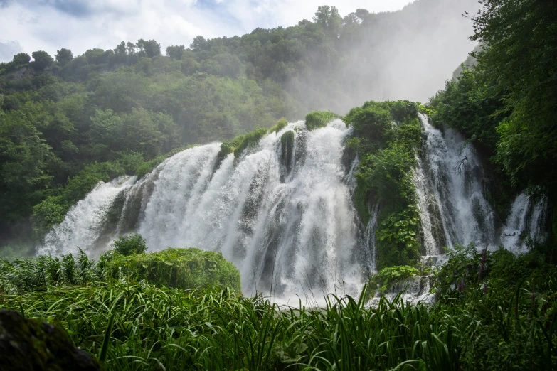 a waterfall with large white cascadings and lush green trees