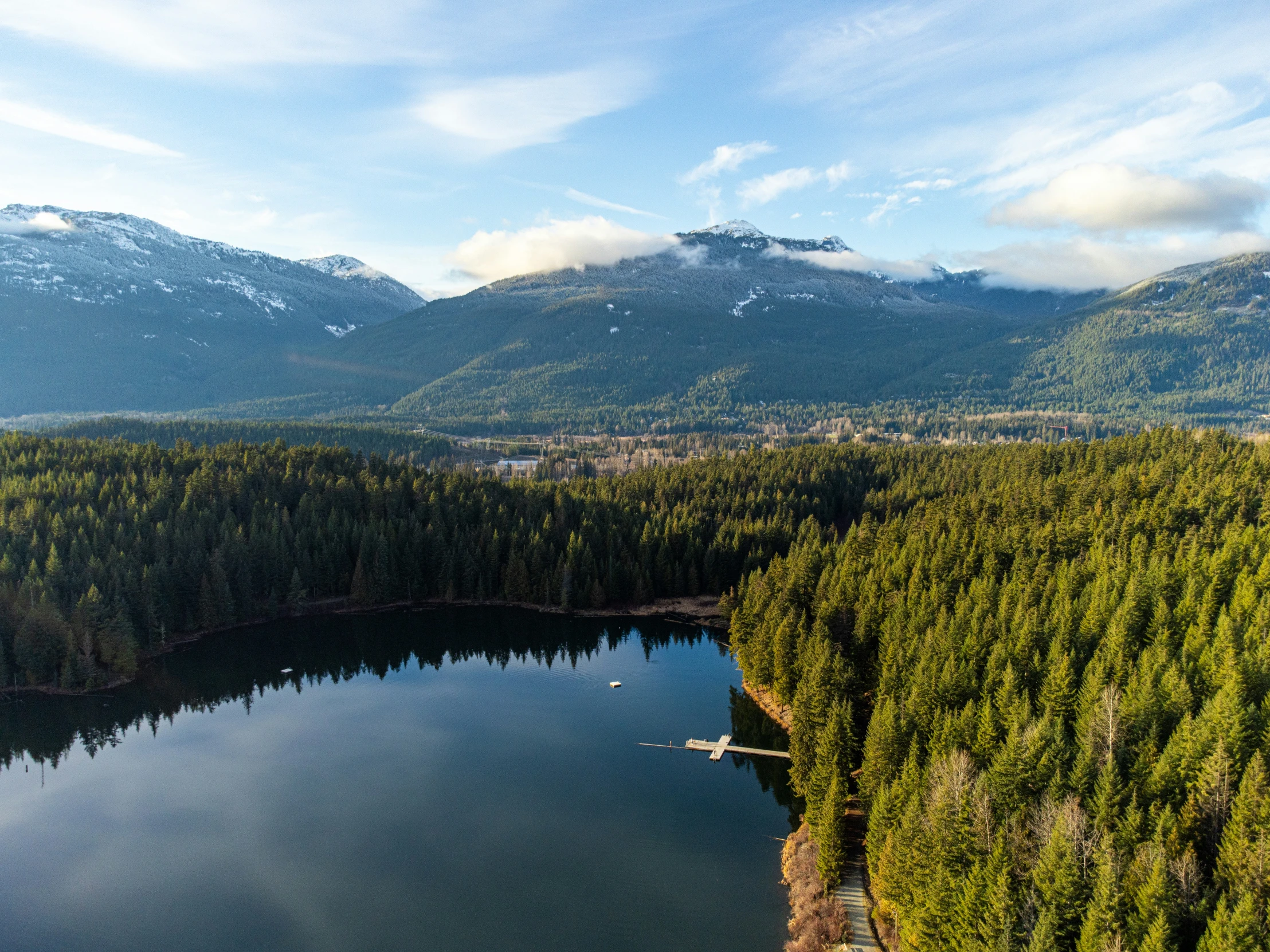 a bird's eye view of a beautiful lake with snow capped mountains