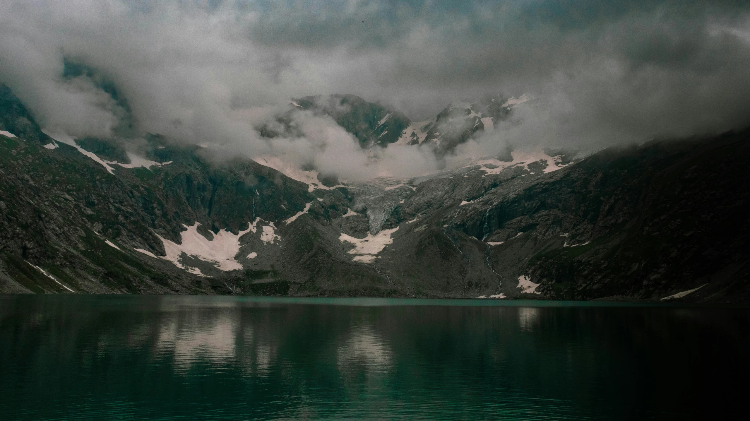 a lake in front of mountains with snow