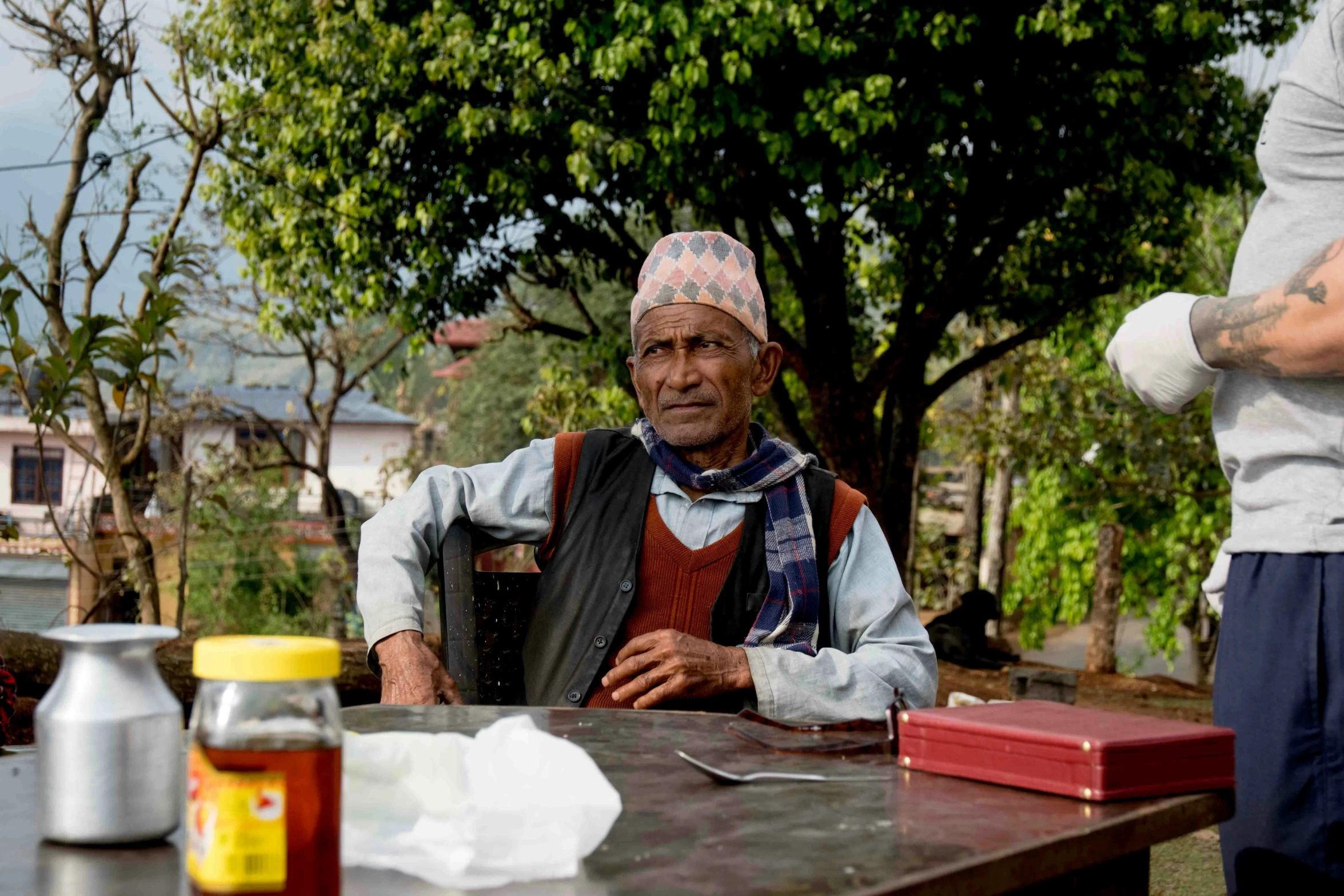 an elderly person sitting in front of a table outside