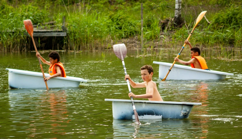 two boys rowing oars and a paddle in their canoes