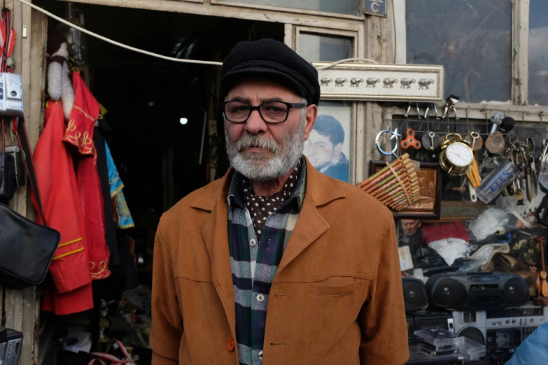 a man wearing a coat and hat stands in front of an outdoor craft shop