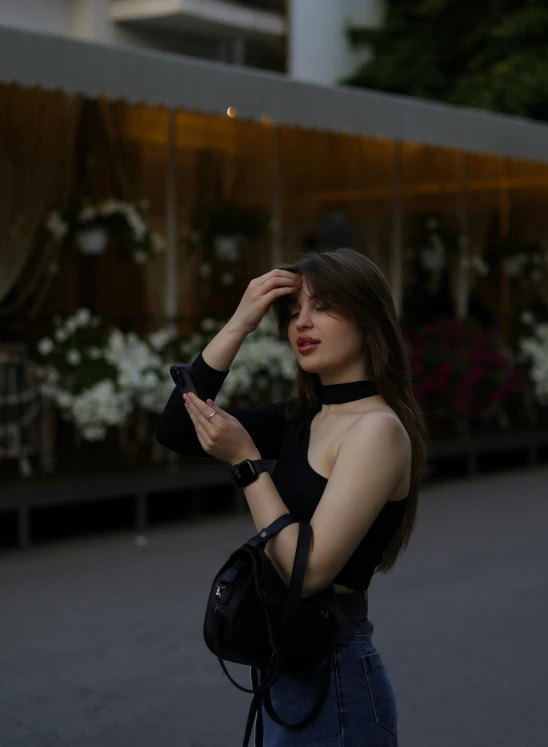 a woman in a black top is holding her hand up to her hair