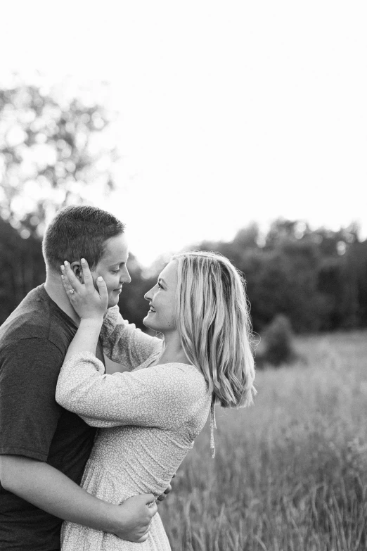 a pregnant couple kissing in the field in their rural setting