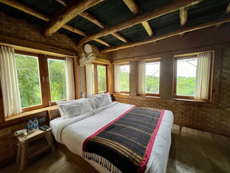 a bed in a room with wooden floors and large windows