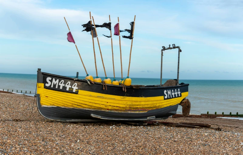 a yellow and black boat sitting on top of a beach