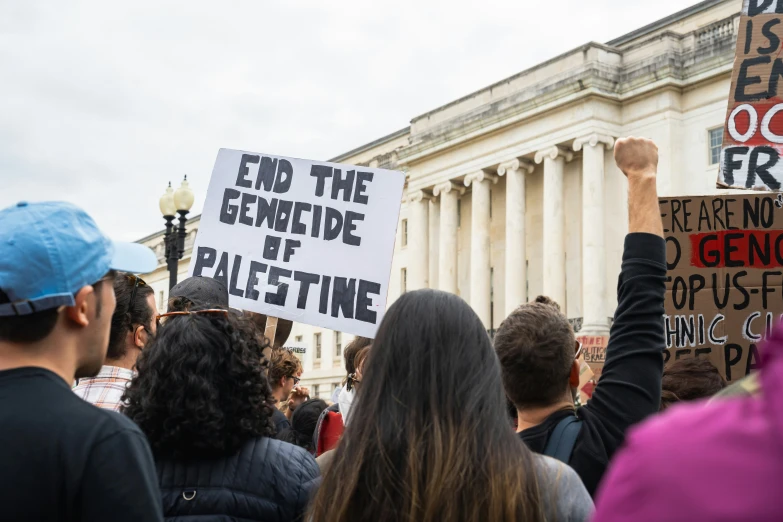 a protest outside of a building with people holding up protest signs