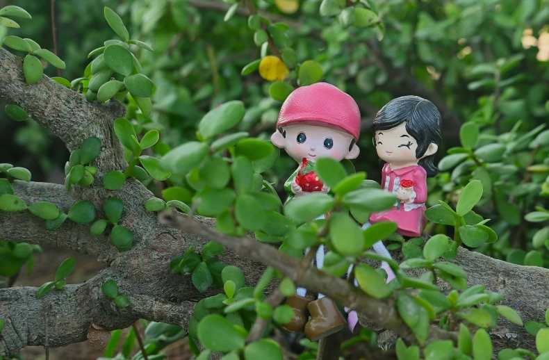 two little figurines sit next to each other in a tree