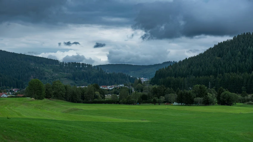 clouds rolling over a lush green hill and the town