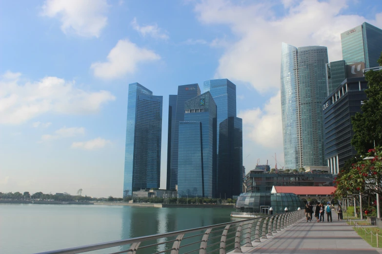 a boardwalk over the water with many tall buildings in front