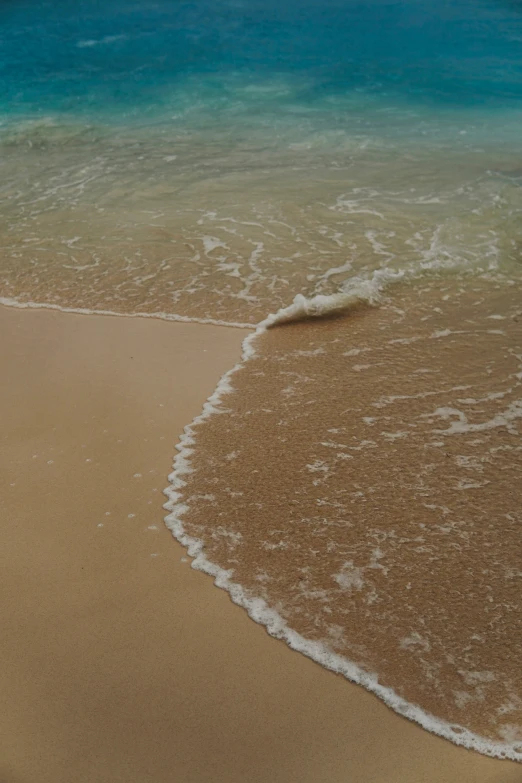 a small wave coming in towards an empty beach