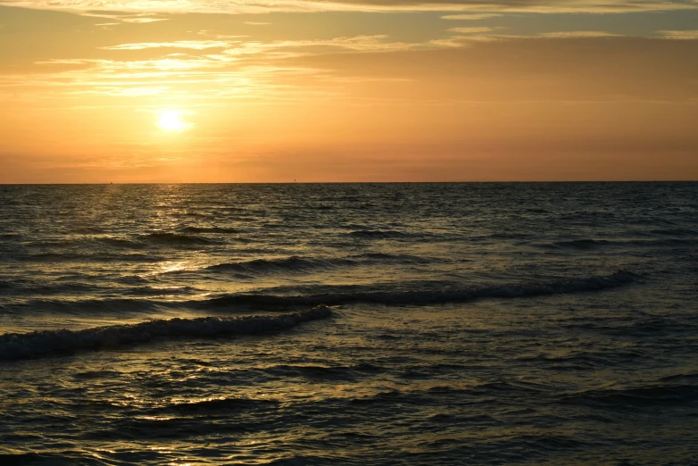 a beautiful sunset on the ocean with waves