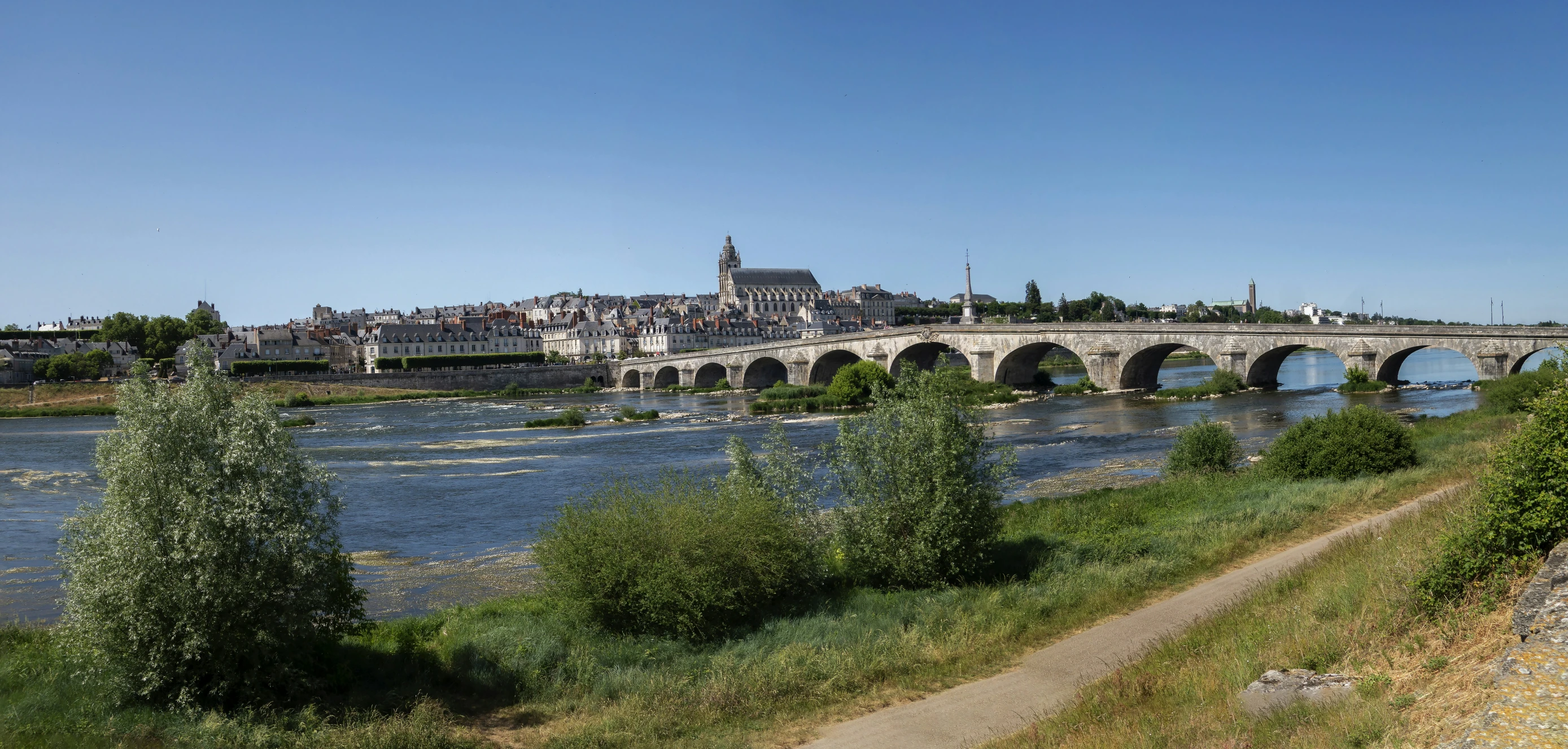 a stone bridge over a river with some people walking across it