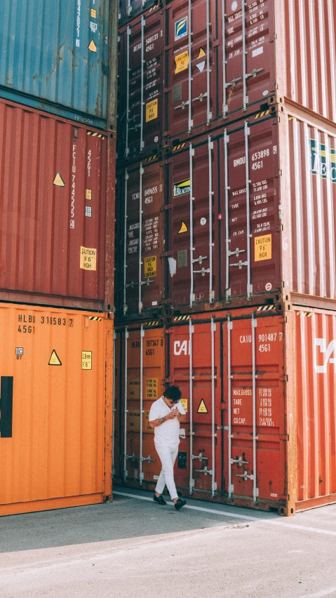 man wearing white walks through a large shipping dock