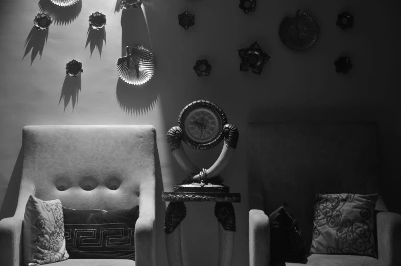 chairs and clocks are sitting against the wall in black and white