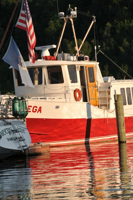 red and white boat parked next to dock with american flag