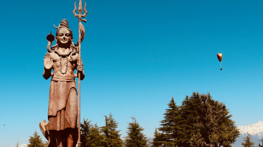 a statue with a small figure next to it and a kite in the air