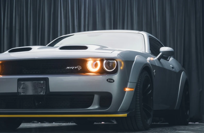 the silver sports car sits parked in front of a curtain