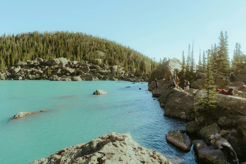 people are standing in the water next to rocky banks