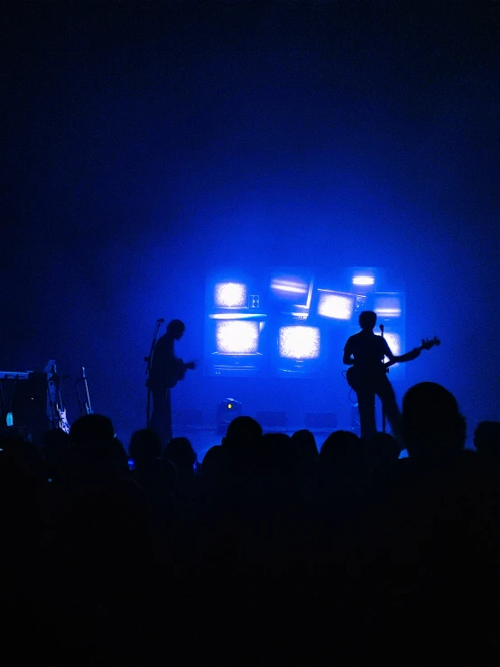 a crowd of people watching two guitar players on stage