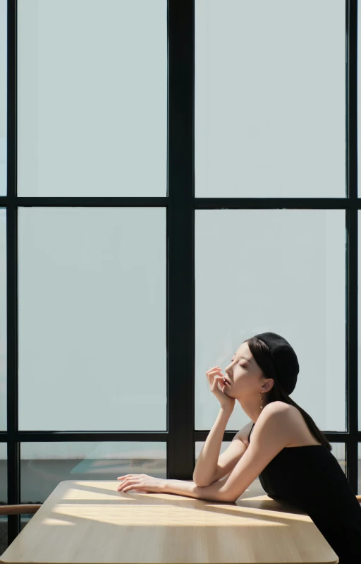 a woman sitting on the edge of a bench next to a window