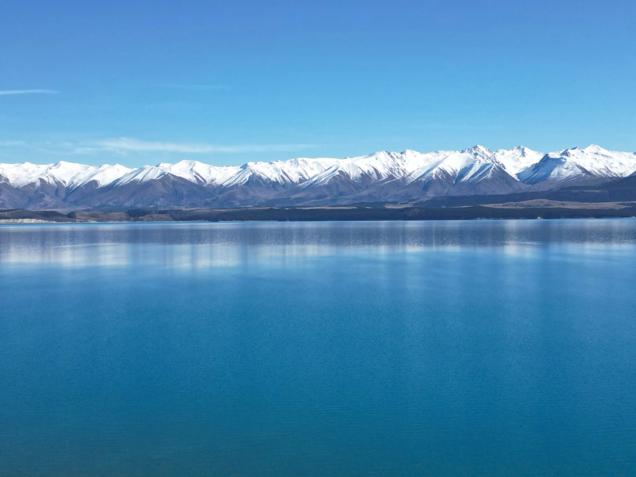 an airplane flying over a lake on a sunny day