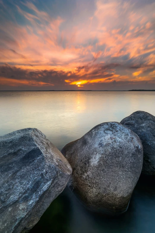 three rocks sit in water near a beach