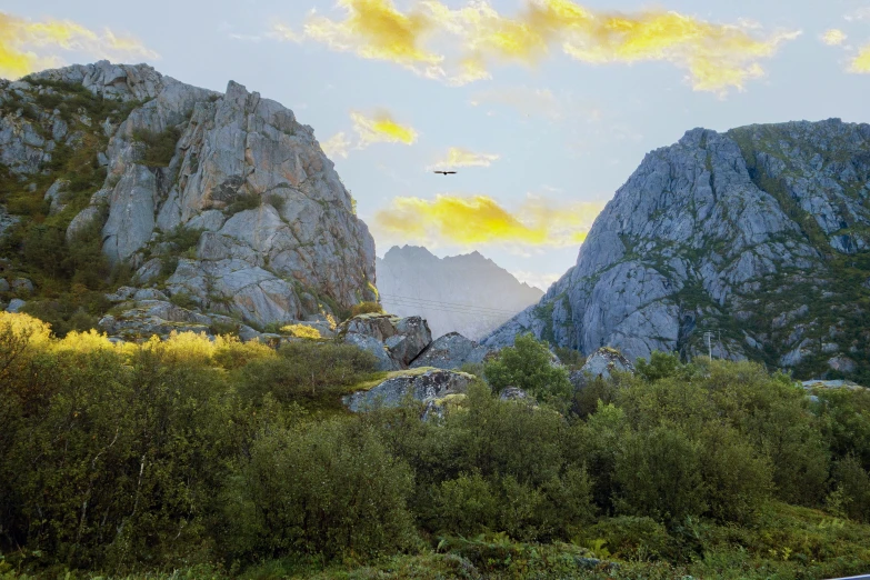 a rocky cliff and the setting sun casts on a hazy sky