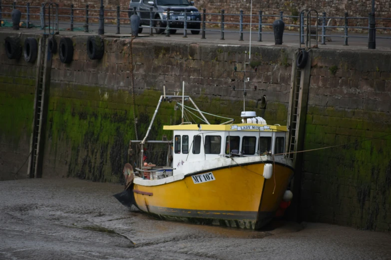 a yellow and white boat with a black truck in the background