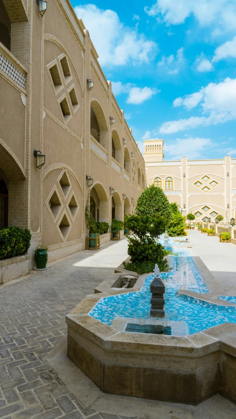 a courtyard with a fountain and statues near buildings