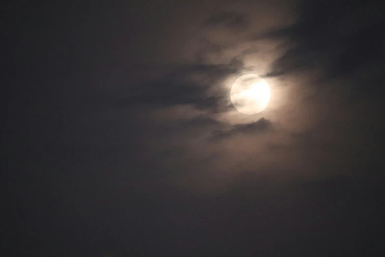 a full moon is visible behind some clouds