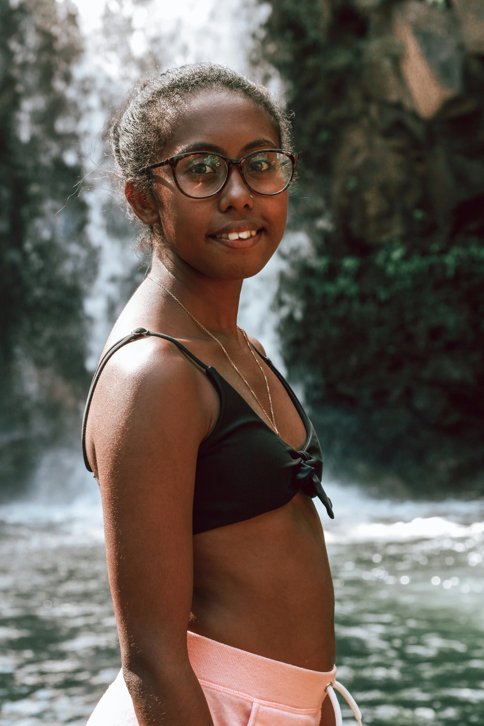 a girl is standing in the water at a waterfall